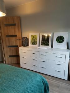 Un dormitorio con una cómoda blanca con dos fotos. en Apartament z widokiem na Zamek en Malbork