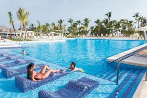 a woman sitting on a blue chair in a pool of water at Riu Republica - Adults Only - All Inclusive in Punta Cana