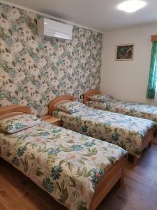 drie bedden in een kamer met bloemenbehang bij Domačija Bubec in Ilirska Bistrica