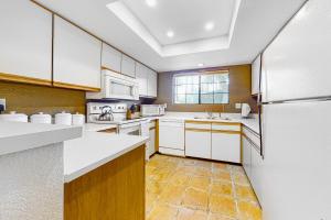 eine Küche mit weißen Schränken und einem Kühlschrank in der Unterkunft Mesquite Bungalow Permit# 1784 in Palm Springs + 13 Fotos