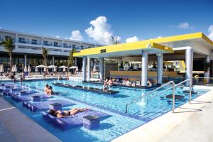 a swimming pool with several chairs and umbrellas at Riu Republica - Adults Only - All Inclusive in Punta Cana
