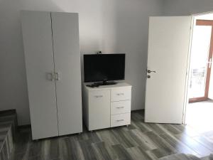 een woonkamer met twee witte kasten en een televisie bij CasaRiana 5 in Eforie Sud