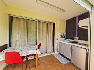 a kitchen with a table and red chairs and a window at Studio Résidence Tobago in Sainte-Anne