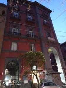 un edificio alto rojo con un árbol delante de él en B&B Museum, en Nápoles