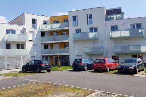 un parking avec des voitures garées devant un bâtiment dans l'établissement T2 moderne, lumineux, proche de la mer et des principaux accès routiers, à Saint-Nazaire