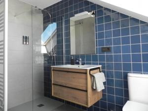a blue tiled bathroom with a sink and a mirror at El Ático in Astorga