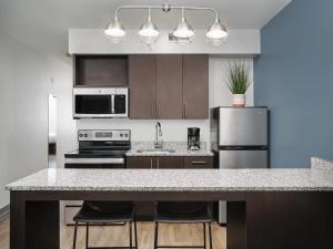 a kitchen with a counter with stools and a refrigerator at stayAPT Suites Goldsboro-Seymour Johnson AFB in Goldsboro