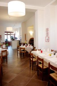 a dining room with white tables and wooden chairs at Paneolio Food and Drink B&B in Poggio Picenze