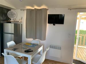 une petite salle à manger avec une table et des chaises blanches dans l'établissement Mobil-home Dan Dom, à Saint-Hilaire-de-Riez