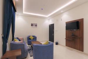 ein Wohnzimmer mit 2 blauen Stühlen und einem Flachbild-TV in der Unterkunft فرس ابها للاجنحة الفندقية in Abha
