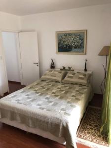 Casa Gramado Vista para o Vale - Parte Térrea في غرامادو: غرفة نوم بسرير ودهان على الحائط