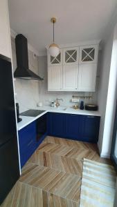 cocina con armarios azules y blancos y suelo de madera en Apartament Hetmański Zamość Stare Miasto parking podziemny, en Zamość