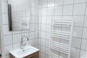 La salle de bains est pourvue de carrelage blanc, d'un lavabo et d'un miroir. dans l'établissement Charming Apt With Garden In Pilat Plage, à La Teste-de-Buch