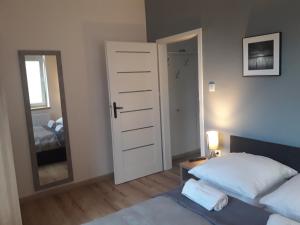 Schlafzimmer mit einem weißen Bett und einem Spiegel in der Unterkunft Apartament City Center Silver - bezpłatny parking in Krynica-Zdrój
