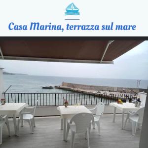 un restaurant avec des tables et des chaises blanches et l'océan dans l'établissement Casa Marina, La Terrazza Sul Mare, à Cefalù