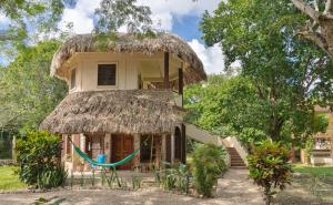 uma casa com um telhado de palha com uma rede na frente em Villas Ecotucan em Bacalar