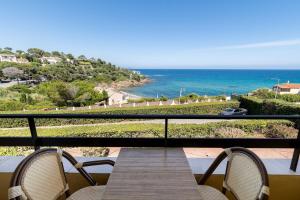 einen Balkon mit einem Holztisch, Stühlen und Meerblick in der Unterkunft "Cap Riviera" Hotel & Restaurant Saint Aygulf in Saint-Aygulf