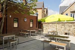 a group of tables and benches with an umbrella at YHA Cambridge in Cambridge