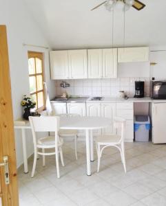 a white kitchen with a white table and chairs at Erdei házak in Csopak