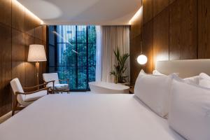 a bedroom with a white bed and a large window at Elcielo Hotel & Restaurant in Medellín