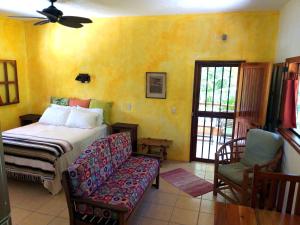 a bedroom with a bed and a couch and a window at Mayan Beach Garden in El Placer