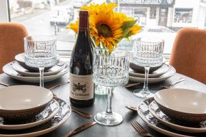 a bottle of wine and glasses on a table with a sunflower at Lonsdale house by Orenda-Luxe in Llandudno +8 photos