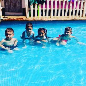 vier Kinder sitzen in einem Pool in der Unterkunft Las Dunas Surf Resort in Aposentillo