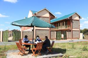 a group of people sitting at a table under an umbrella at The 4 JS Bed and Breakfast Emali in Emali