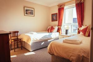 a bedroom with two beds and a chair and a window at The Links Apartment Portrush in Portrush