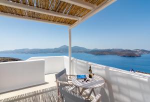 una mesa y sillas en un balcón con vistas al océano en Plaka Suites en Plaka Milou