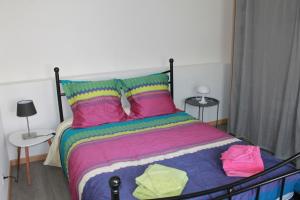 Gite de l'ancien Moulin في لو فال ديه آجول: غرفة نوم مع سرير مع أوراق ووسائد ملونة