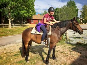 a young girl is sitting on a horse at Nordic Refuge B&B in Fröskog