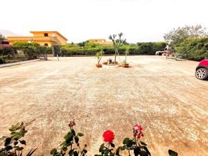 Un parking avec des fleurs rouges au milieu dans l'établissement Frida casavacanze, à Castellammare del Golfo