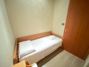 ein kleines Bett in einem kleinen Zimmer mit einer Holztür in der Unterkunft La casa di nonna rosetta in Cirò Marina