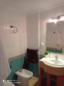 a bathroom with a sink and a toilet and a mirror at Precioso ático con solárium y vistas fantásticas in Playa Honda