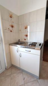 a white kitchen with a stove and a sink at Apartments Raos Podgora in Podgora