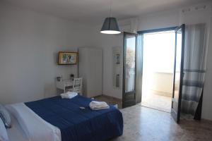 ein Schlafzimmer mit einem blauen Bett und einer Glasschiebetür in der Unterkunft Bahari Beachfront Aparthotel Selinunte in Marinella di Selinunte