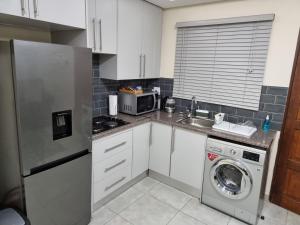 a kitchen with white cabinets and a washer and dryer at Koena Court (Unit 2) - With Uncapped Fiber Wi-Fi in Midrand