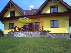 a yellow house with a porch with an umbrella at apartman Happy in Stará Lesná