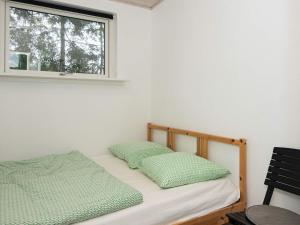 a bedroom with a bed with two green pillows at 5 star holiday home in Knebel in Knebel