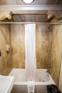 a bathroom with a tub and a white shower curtain at Chama Trails Motel in Chama