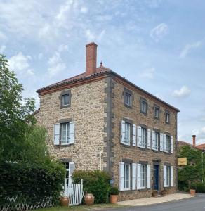 a brick building with white windows on a street at La maison de Maria in Saint-Beauzire