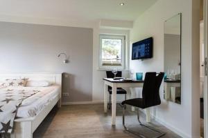 een slaapkamer met een bed, een bureau, een bed en een raam bij Gartenwohnung-Landhaus-Tadsen in Westerland