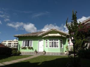 a green house with a white door in a yard at Casa Verde - Suíte 2 - Iúcas, Teresópolis, RJ in Teresópolis