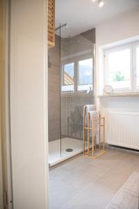 a bathroom with a shower with a chair and a table at Mountain Mama Ferienhaus in Schliersee