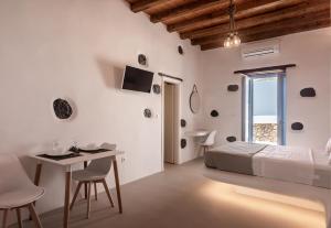 a white bedroom with a bed and a table and chairs at Plaka Suites in Plaka Milou