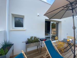 een patio met een tafel en stoelen en een parasol bij Suite pour deux in La Jarne