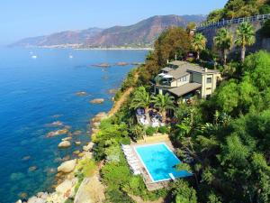 a house with a swimming pool next to a body of water at Villa Anita Apartments in Capo dʼOrlando