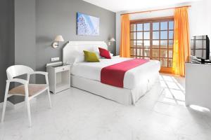 a bedroom with a bed and a desk and a tv at Elba Castillo San Jorge & Antigua Suite Hotel in Caleta De Fuste
