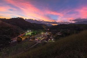 a view of a town with a sunset in the mountains at Resort Fazenda 3 Pinheiros in Engenheiro Passos